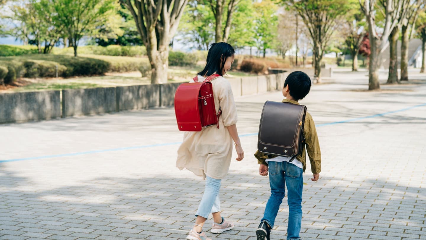 ランドセルを背負った小学生の男女二人が、歩きながら話している写真